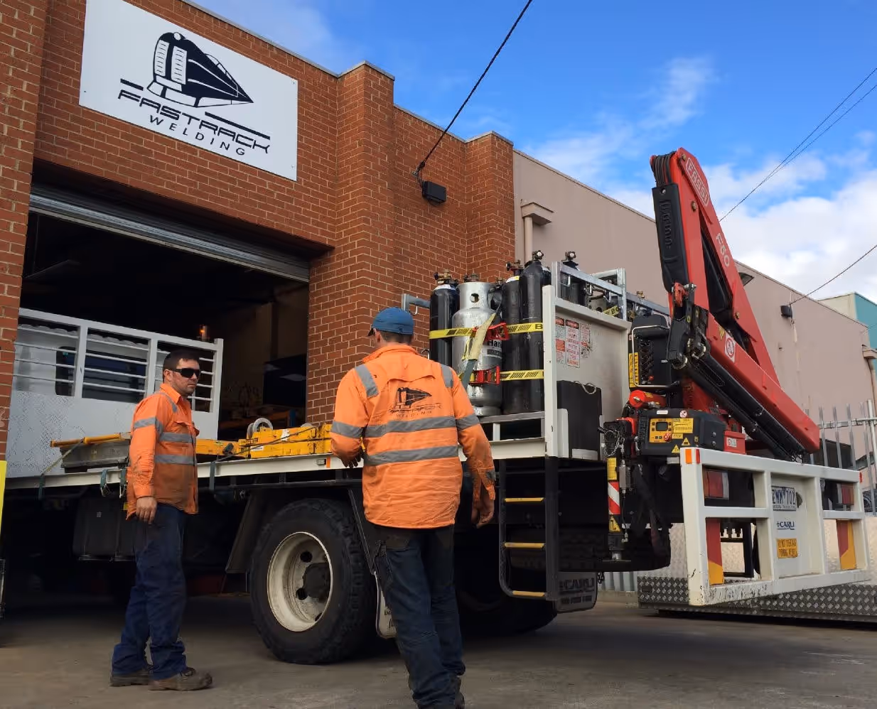 The front of the Fast Track Welding workshop, with a truck and two staff members.