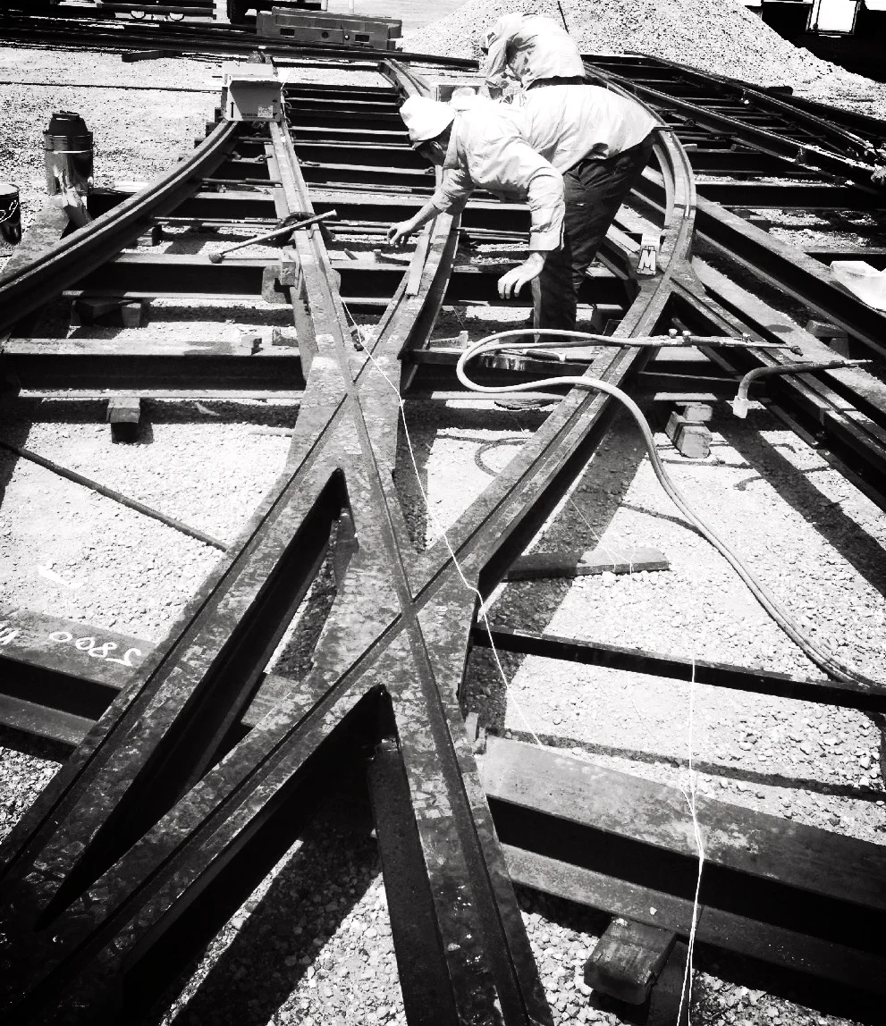 Two Fast Track Welding crew working a rail crossing with welding leads run out.