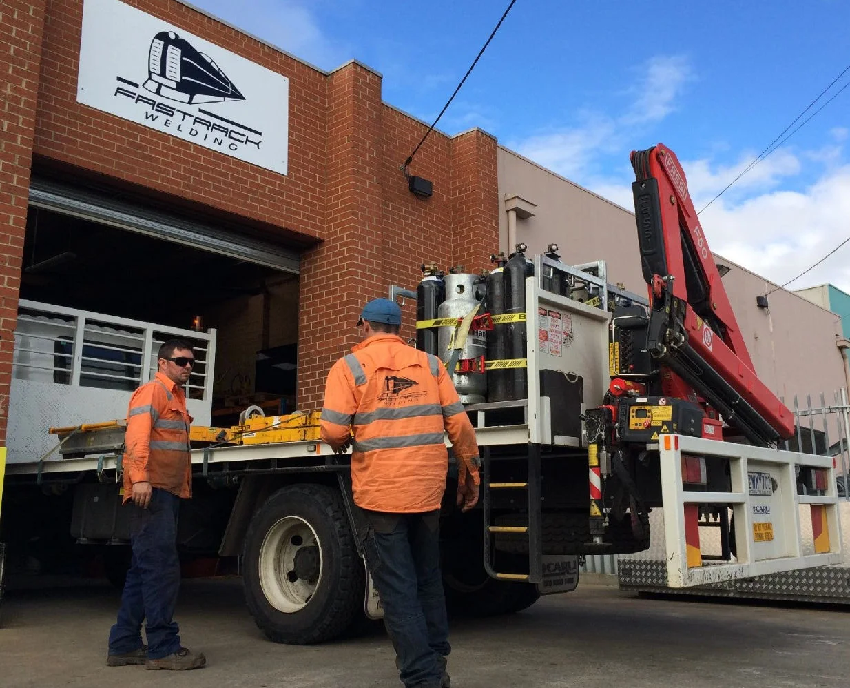 The front of the Fast Track Welding workshop, with a truck and two staff members.